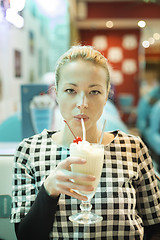 Image showing Woman drinking milk shake in diner.