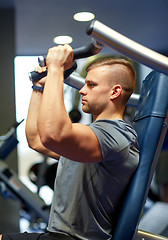 Image showing man exercising and flexing muscles on gym machine