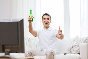 Image showing smiling man watching tv and drinking beer at home