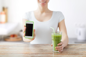 Image showing close up of woman with smartphone and green juice