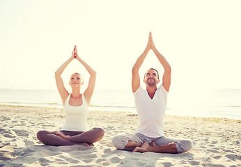 Image showing smiling couple making yoga exercises outdoors