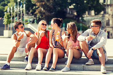 Image showing group of smiling friends sitting on city square