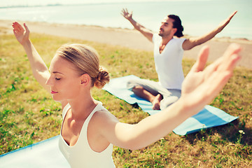 Image showing smiling couple making yoga exercises outdoors