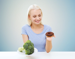 Image showing smiling woman choosing between broccoli and donut