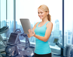 Image showing smiling sporty woman with tablet pc in gym