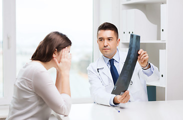 Image showing smiling male doctor in white coat looking at x-ray