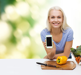 Image showing smiling woman with smartphone cooking vegetables