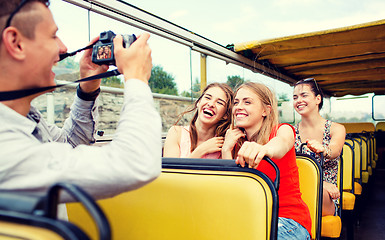 Image showing laughing friends with camera traveling by tour bus