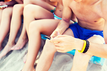 Image showing close up of friends with smartphones on beach