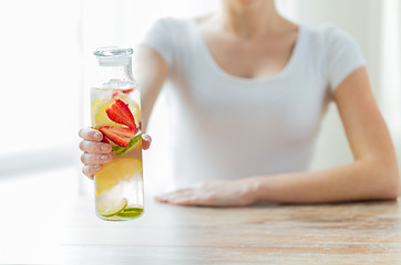 Image showing close up of woman with fruit water in glass bottle