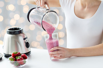 Image showing close up of woman with blender pouring milk shake