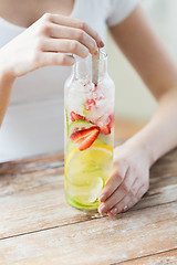 Image showing close up of woman with fruit water in glass bottle