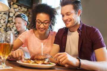 Image showing happy friends eating and drinking at bar or pub