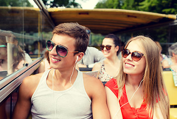 Image showing smiling couple with earphones traveling by bus