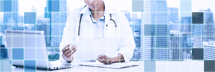 Image showing female doctor with laptop pc looking at paper