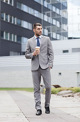 Image showing young serious businessman with paper cup outdoors