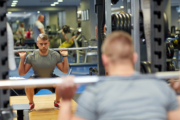 Image showing young man flexing muscles with barbell in gym