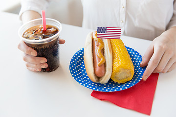 Image showing close up of woman eating hot dog with coca cola