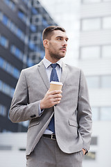 Image showing young serious businessman with paper cup outdoors