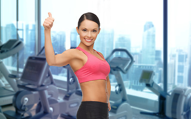 Image showing smiling asian woman showing thumbs up over gym