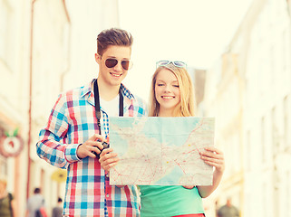 Image showing smiling couple with map and photo camera in city