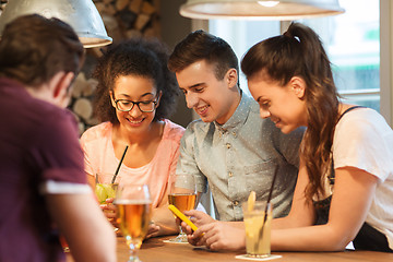 Image showing happy friends with smartphones and drinks at bar