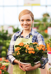 Image showing happy woman holding flowers in greenhouse