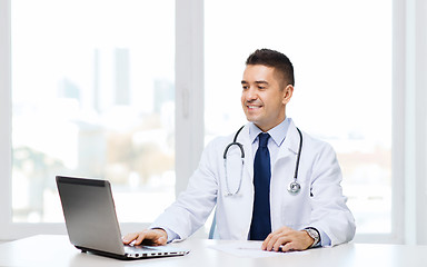 Image showing smiling male doctor with laptop in medical office