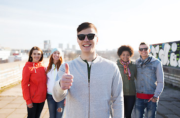 Image showing happy teenage friends showing thumbs up on street