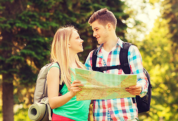 Image showing smiling couple with map and backpacks in forest