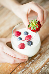 Image showing close up of woman hands with yogurt and berries