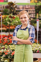 Image showing happy woman with flowers in greenhouse