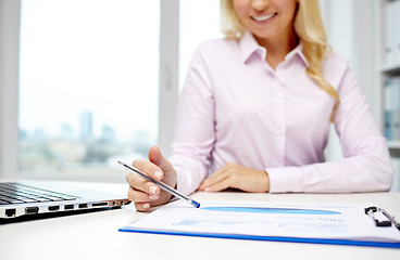 Image showing smiling businesswoman reading papers in office