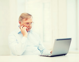 Image showing old man in eyeglasses working with laptop at home