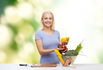 Image showing smiling young woman cooking vegetables over green