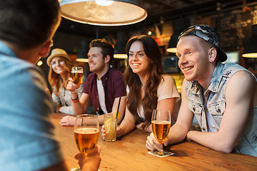 Image showing happy friends with drinks talking at bar or pub