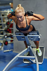 Image showing young woman flexing back muscles on bench in gym