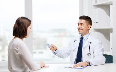 Image showing smiling doctor giving pills to woman at hospital