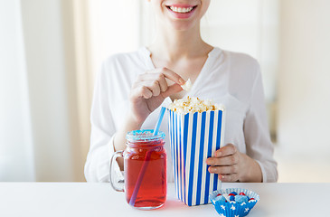 Image showing woman eating popcorn with drink in glass mason jar