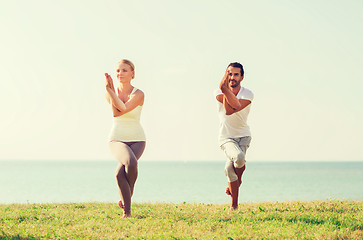 Image showing smiling couple making yoga exercises outdoors