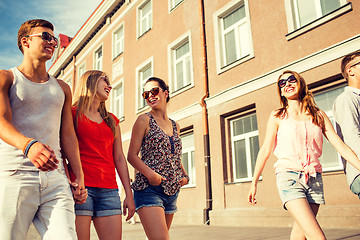 Image showing group of smiling friends walking in the city