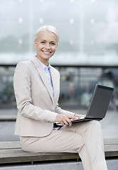 Image showing smiling businesswoman working with laptop outdoors