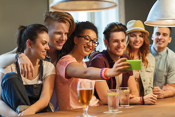 Image showing happy friends with smartphone taking selfie at bar