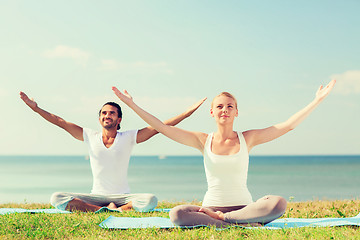 Image showing smiling couple making yoga exercises outdoors