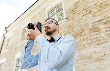 Image showing happy young hipster man with film camera in city