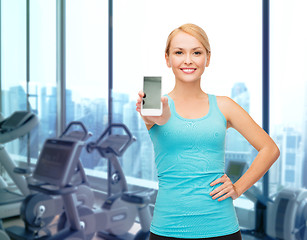 Image showing smiling sporty woman showing smartphone in gym