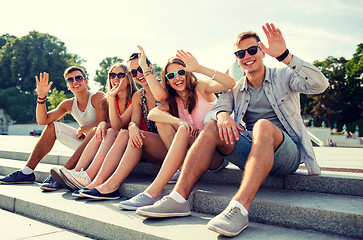 Image showing group of smiling friends sitting on city street