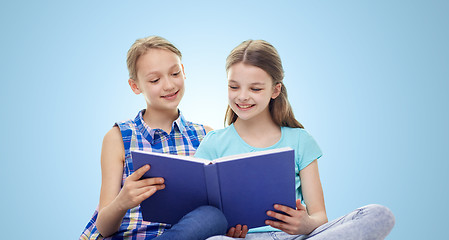 Image showing two happy girls reading book over blue background