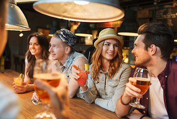 Image showing happy friends with drinks talking at bar or pub