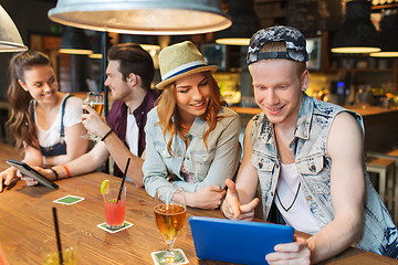 Image showing happy friends with tablet pc and drinks at bar